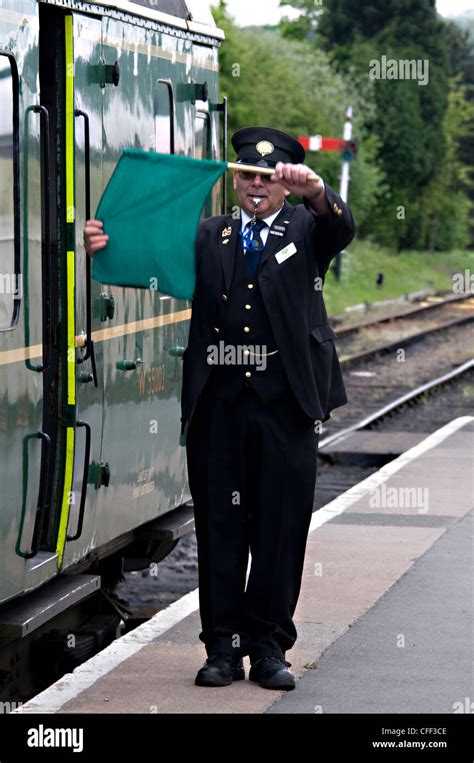 train guard blows  whistle  waves  green flag  departure