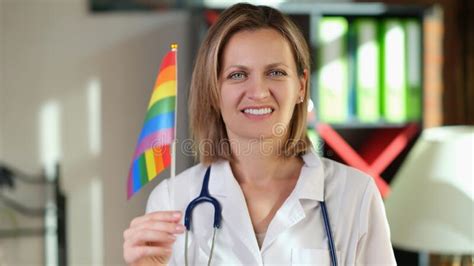 Smiling Female Doctor With Lgbt Flag In Her Hand In Clinic Office