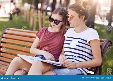 female classmates sit closely    read information   book  sit  wooden
