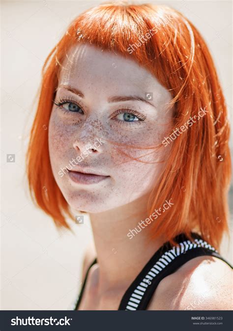 closeup portrait of a beautiful ginger redhead teen girl with blue eyes and freckles natural