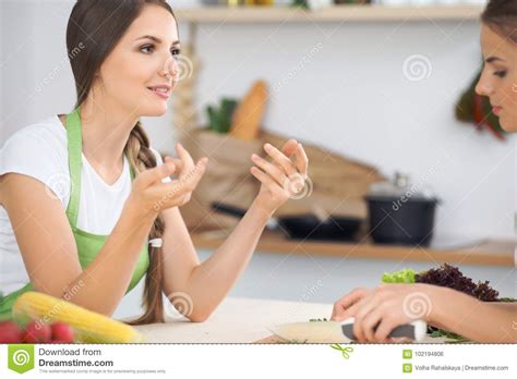 Two Women Friends Cooking In Kitchen While Having A
