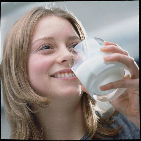 teenage girl drinking a glass of milk photograph by damien lovegrove