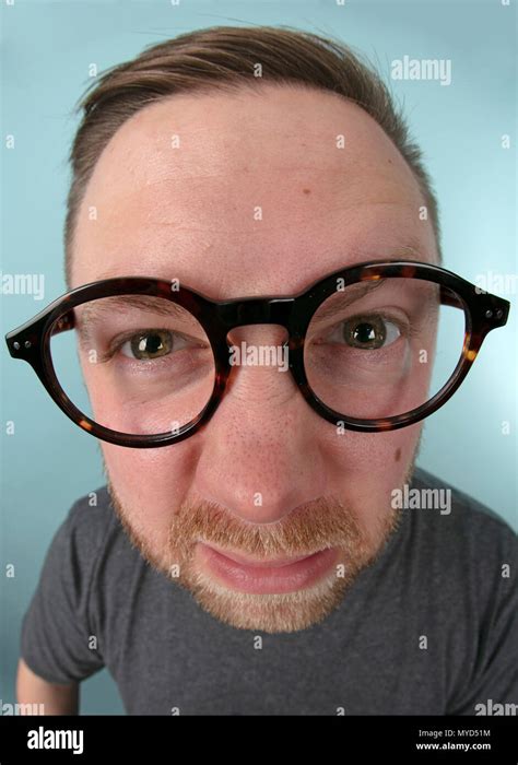 Man Wearing Large Glasses Stretching Forwards To Peer Into The Lens In