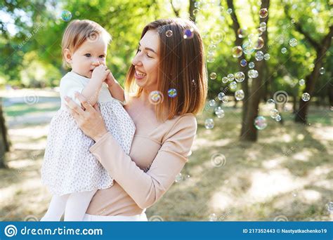 happy mother and daughter blowing bubbles in the park stock image