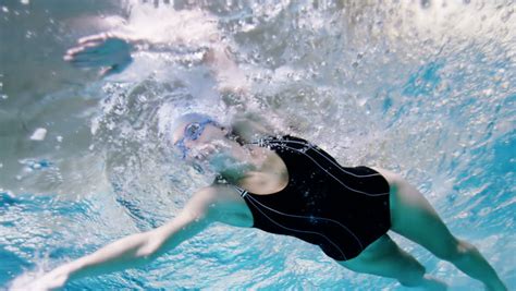 view from underneath of a professional female swimmer underwater with a bright light reflecting