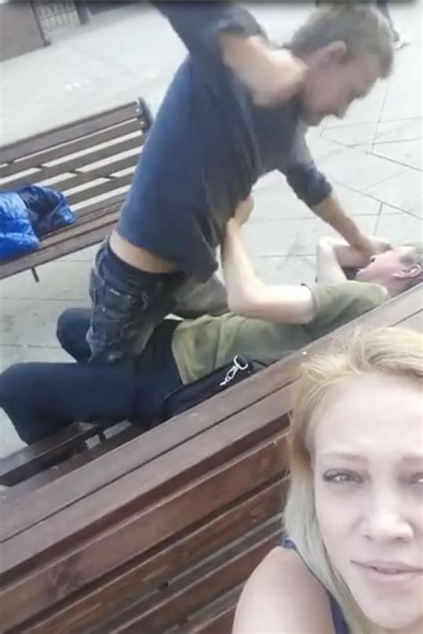 smirking girl films street brawl on her phone camera while