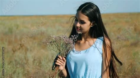 young beautiful girl   blue dress enjoys flowers steppe  young woman   meadow steppe