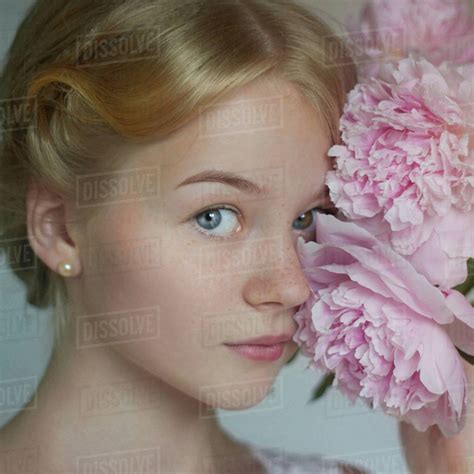 Close Up Of Caucasian Teenage Girl Holding Flowers To Face Stock