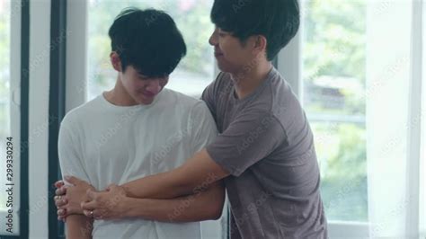 Asian Gay Couple Standing And Hugging Near The Window At Home Young