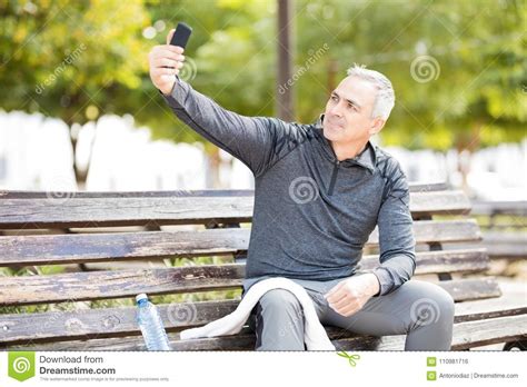 mature man taking a selfie after exercising in park stock