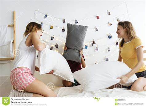Group Of Diverse Women Playing Pillows Fight On Bed Together Stock