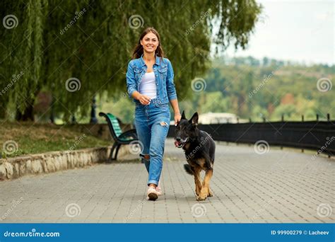 Una Chica Joven Está Caminando Con Un Perro En El Parque Imagen De