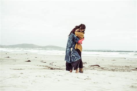 same sex lesbian couple hug on wild remote beach adventure in the wind