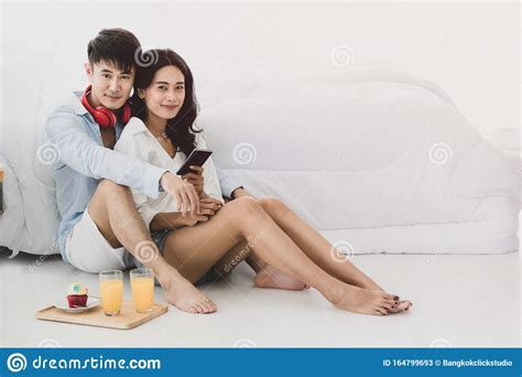 Asian Couple Sitting On The Floor In The Bedroom Stock