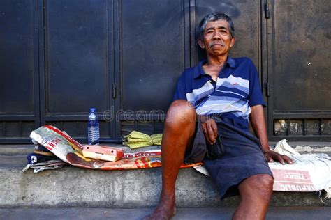 A Mature Filipino Man Rests On A Sidewalk And Poses For The Camera