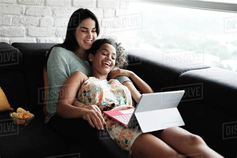 Happy Lesbian Couple Watching Video Over Laptop Computer While Relaxing