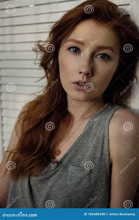 A Beautiful Redhead Girl With Her Hair And Freckles In A Gray T Shirt