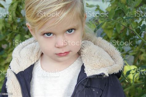 outdoor portrait of 3 years old cute blonde girl looking at camera