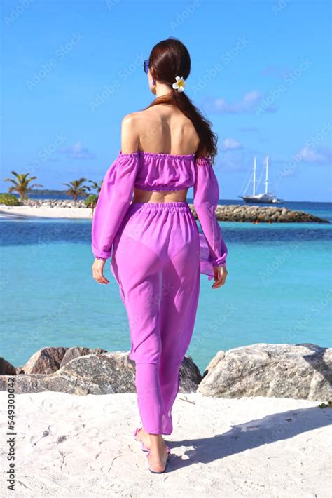beautiful stylish slender girl on the beach in the maldives stands with