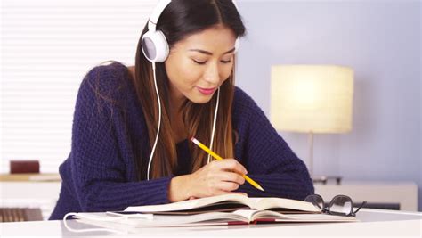 chinese woman listening to music while doing homework stock footage video 6819847 shutterstock