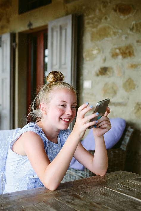 Preteen Girl Laughing While Holding Her Mobile Telephone By Helen