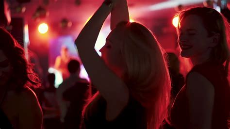 friends dancing in the spotlight at a disco in a nightclub girls