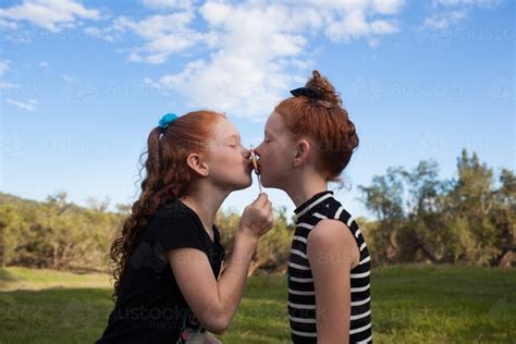 Image Of Two Girls Outside Kissing A Rainbow Lollipop Austockphoto