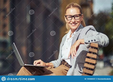 linda mulher de meia idade bem sucedida vestindo pestanas sentada  banco ao ar livre