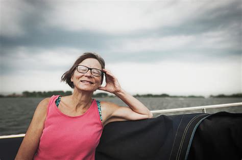 Smiling Mature Woman Sitting On Boat Against Cloudy Sky Photograph By