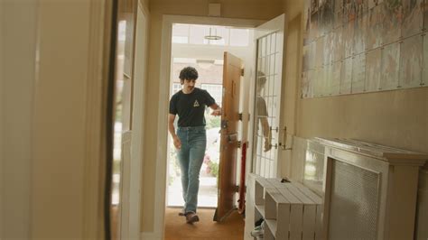 man opens door entering hallway putting  keys  walks  stairs