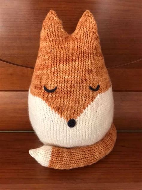 A Knitted Fox Sitting On Top Of A Wooden Bench