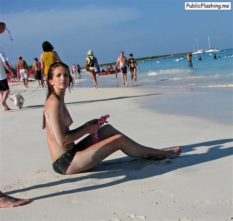 teen brunette is sitting in the sand topless