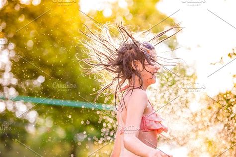 girl in bikini dancing at the sprinkler summer garden featuring weather