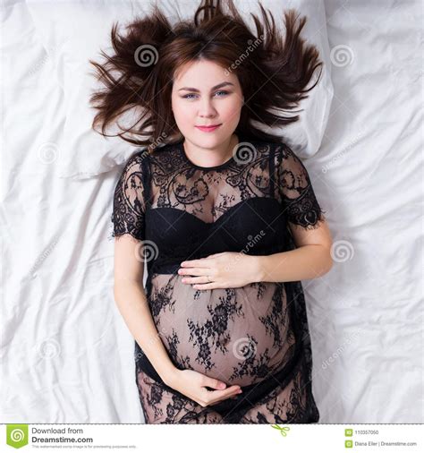 Portrait Of Pregnant Woman In Black Lace Lingerie Lying In Bed Stock