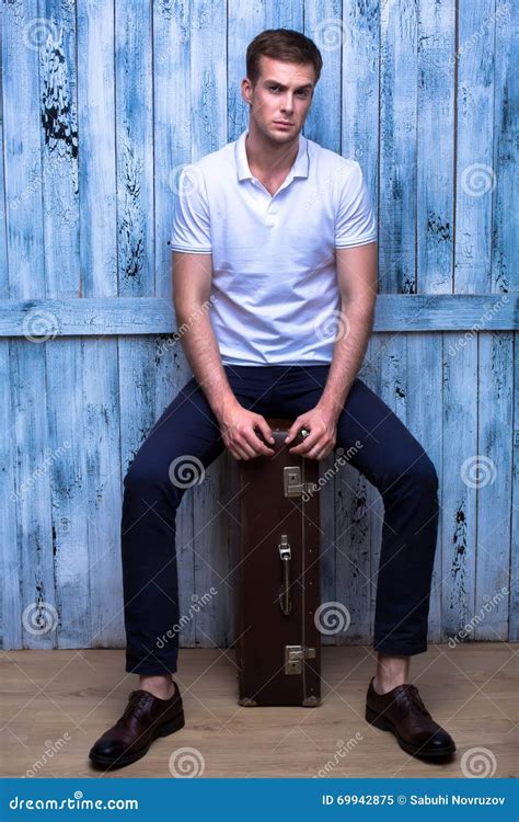 tall handsome guy   white polo shirt sitting    brown stock