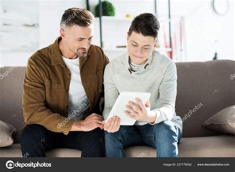 père adolescent fils utilisant tablette assis sur canapé maison image