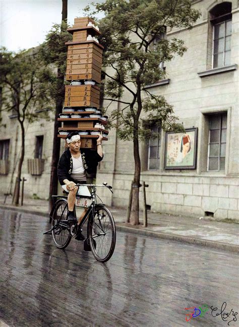 A Japanese Man Rides His Bike Carrying Soba Noodles On His Shoulder In