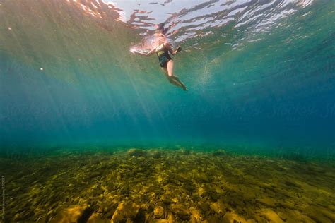 woman swimming underwater in clear summer lake by jp danko swimming