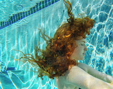 teenage girl  red hair swimming underwater  pool stock photo