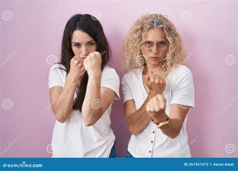 Mother And Daughter Standing Together Over Pink Background Ready To