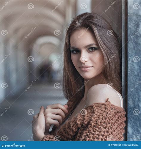 Young Beautiful Brunette In Fashionable Clothes Near The Wall Stock