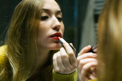 Beautiful Woman Applying Red Lipstick In Front Of A Mirror