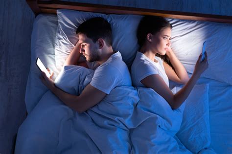esposas infieles usando teléfonos inteligentes acostados en la cama por