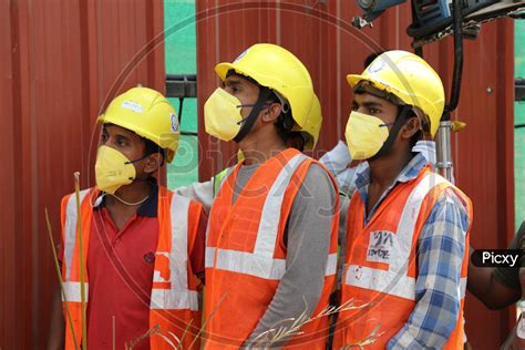 Image Of Construction Workers Wearing Safety Helmets And Masks At A