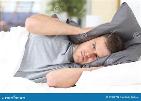 mens die aan slaap proberen die oren voor lawaai behandelen stock foto image  achtergrond