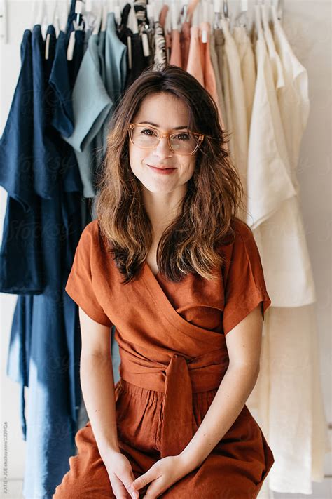 portrait of a woman with glasses in front of her clothing collection