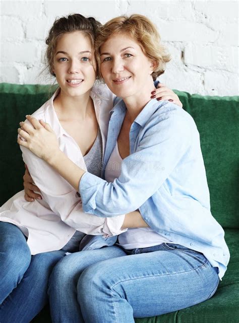 beautiful senior mom and her adult daughter are hugging looking at