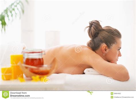woman laying on massage table with honey spa therapy ingredients stock