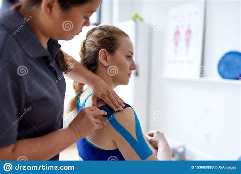 chinese woman massage therapist applying kinesio tape to the shoulders