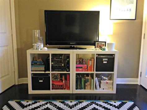 A Flat Screen Tv Sitting On Top Of A White Book Shelf Next To A Black